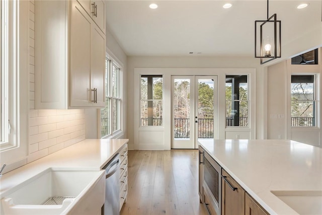 kitchen with hanging light fixtures, dishwasher, plenty of natural light, and decorative backsplash