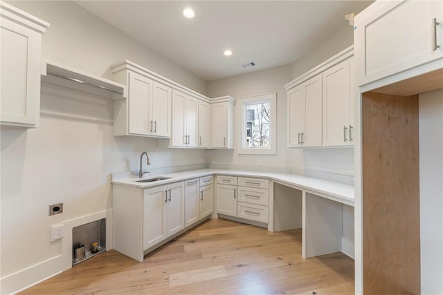 laundry room featuring cabinets, sink, light hardwood / wood-style flooring, and electric dryer hookup