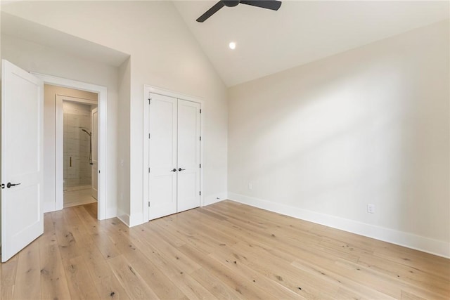 unfurnished bedroom featuring ceiling fan, a closet, high vaulted ceiling, and light hardwood / wood-style flooring