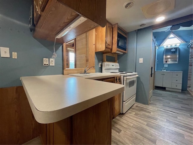 kitchen featuring white electric stove, kitchen peninsula, sink, and light hardwood / wood-style flooring