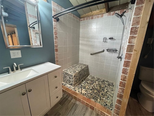 bathroom with vanity, wood-type flooring, a tile shower, and toilet