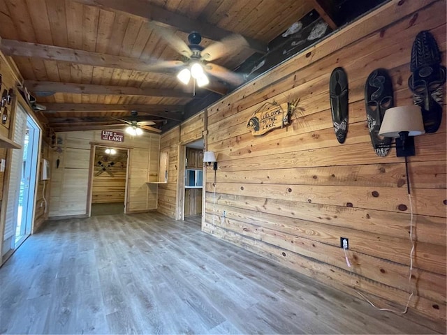 unfurnished living room featuring wood ceiling, wood-type flooring, lofted ceiling with beams, wooden walls, and ceiling fan