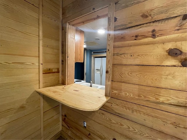 hall featuring sink and wooden walls