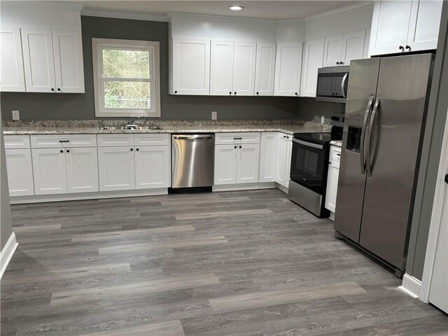 kitchen featuring sink, dark hardwood / wood-style flooring, stainless steel appliances, light stone countertops, and white cabinets