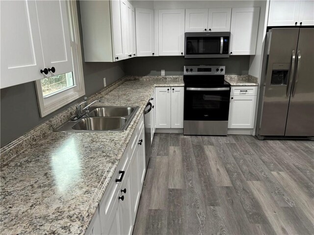 kitchen with appliances with stainless steel finishes, sink, hardwood / wood-style floors, and white cabinets