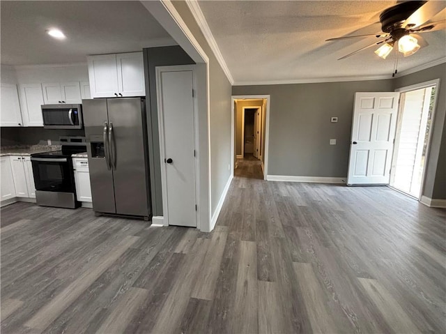 kitchen with hardwood / wood-style flooring, ornamental molding, white cabinets, and appliances with stainless steel finishes