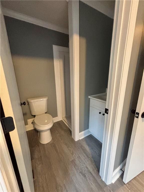 bathroom featuring hardwood / wood-style floors, crown molding, and toilet