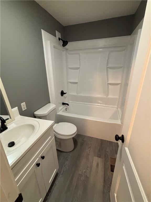 full bathroom featuring wood-type flooring, toilet,  shower combination, and vanity