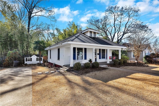 view of front of house featuring an outdoor structure, covered porch, and a front lawn