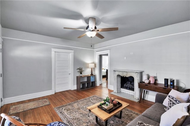 living room featuring ceiling fan, a fireplace, and dark hardwood / wood-style flooring