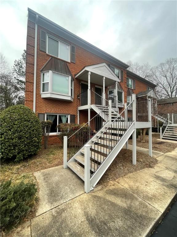 view of front facade with brick siding and stairway