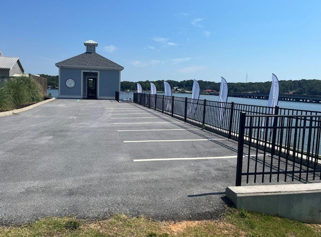 uncovered parking lot featuring fence and a water view