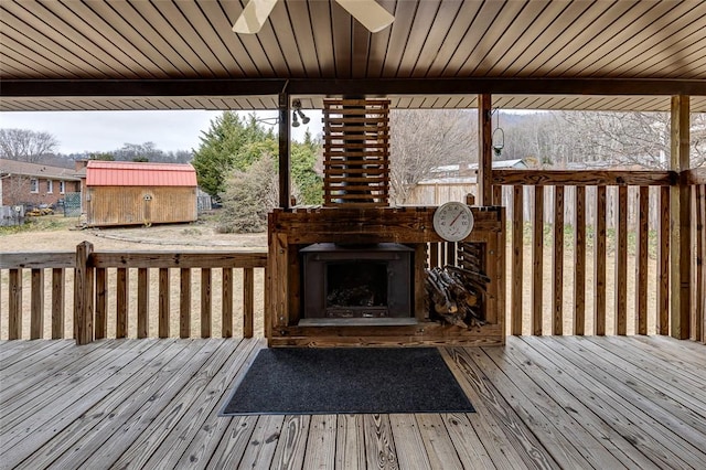 deck with exterior fireplace and ceiling fan