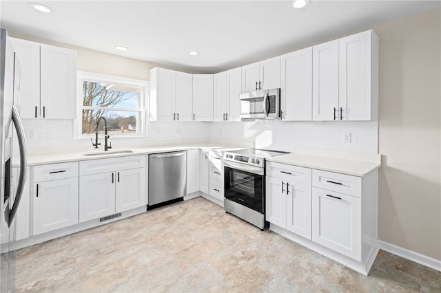 kitchen featuring appliances with stainless steel finishes, sink, white cabinets, and backsplash