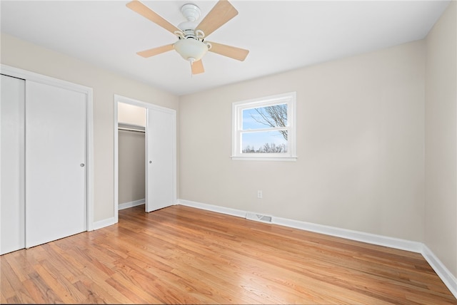 unfurnished bedroom featuring multiple closets, ceiling fan, and light wood-type flooring