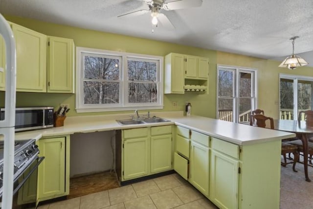 kitchen featuring decorative light fixtures, sink, gas range oven, kitchen peninsula, and a textured ceiling