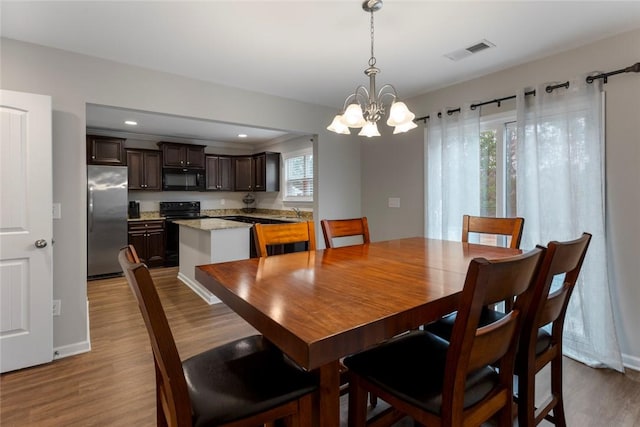 dining area with an inviting chandelier, sink, and light wood-type flooring