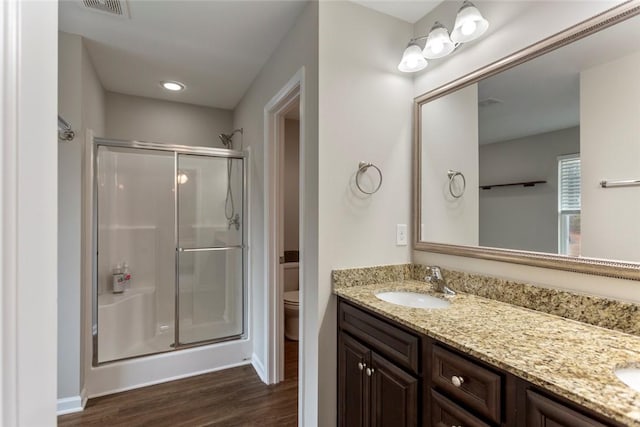 bathroom featuring hardwood / wood-style flooring, vanity, a shower with shower door, and toilet