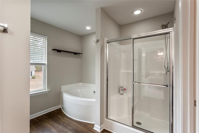 bathroom with a wealth of natural light, wood-type flooring, and separate shower and tub