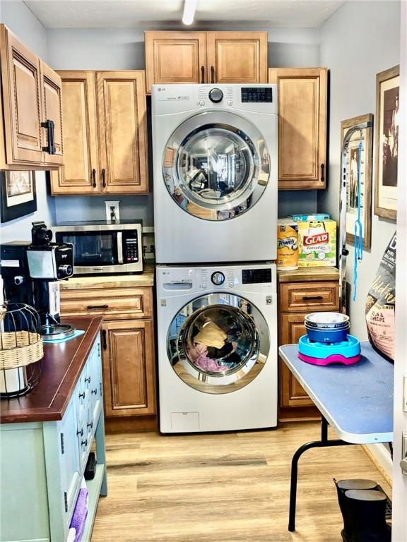 laundry room featuring light hardwood / wood-style floors and stacked washing maching and dryer