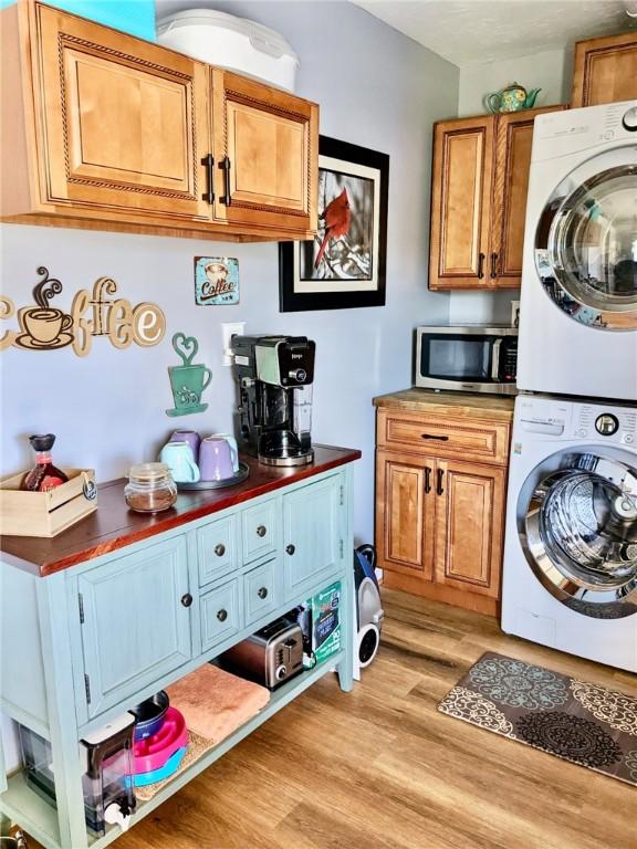 clothes washing area featuring stacked washer / dryer and light hardwood / wood-style flooring