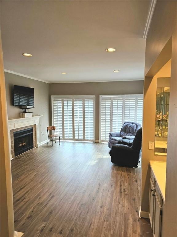 living area with ornamental molding, wood-type flooring, a tiled fireplace, and plenty of natural light