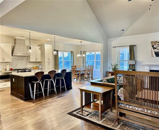 living room with high vaulted ceiling, light hardwood / wood-style flooring, and a notable chandelier