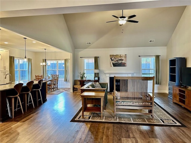 living room with sink, dark hardwood / wood-style floors, ceiling fan with notable chandelier, and high vaulted ceiling