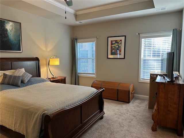 bedroom featuring multiple windows, ornamental molding, a raised ceiling, and light carpet