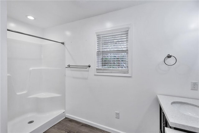 bathroom featuring wood-type flooring, a shower, and vanity