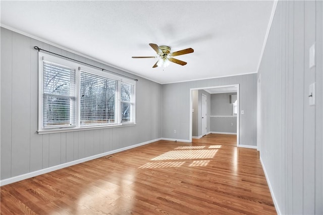 empty room with crown molding, ceiling fan, and light wood-type flooring