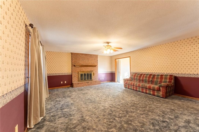 living room featuring a brick fireplace, carpet floors, a textured ceiling, and ceiling fan