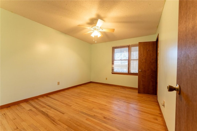 spare room with ceiling fan, a textured ceiling, and light wood-type flooring