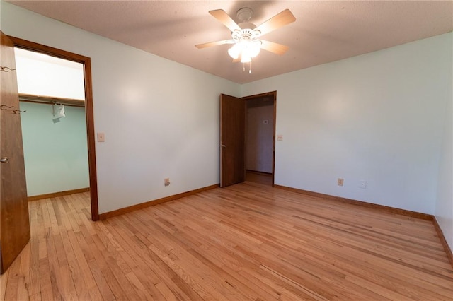 unfurnished bedroom with ceiling fan, a walk in closet, light hardwood / wood-style floors, and a closet