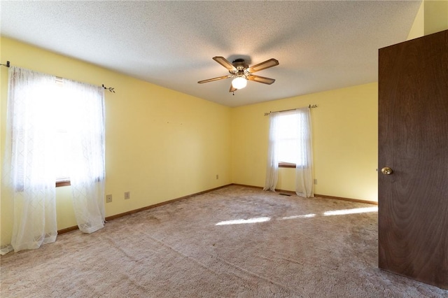 empty room featuring ceiling fan, light colored carpet, and a textured ceiling