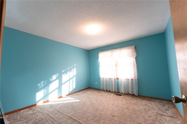 carpeted spare room with a textured ceiling