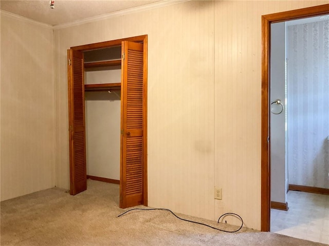 unfurnished bedroom featuring light carpet, crown molding, and a closet