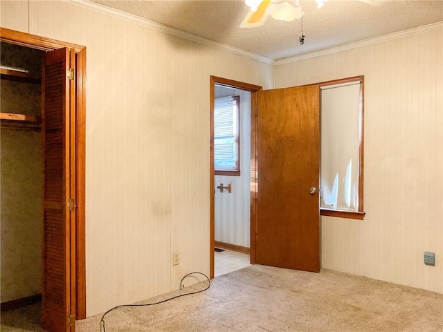 unfurnished bedroom with light carpet, crown molding, a textured ceiling, and ceiling fan