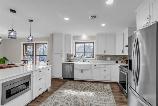 kitchen with white cabinetry, appliances with stainless steel finishes, dark hardwood / wood-style flooring, and decorative light fixtures