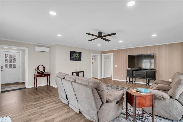 living room with crown molding, hardwood / wood-style floors, ceiling fan, and a wall unit AC