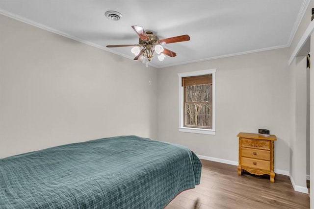 bedroom featuring hardwood / wood-style flooring, crown molding, and ceiling fan