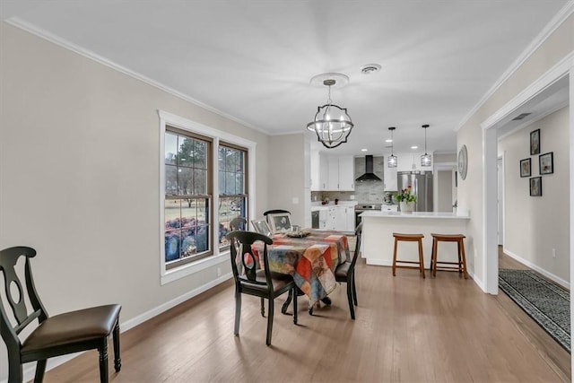 dining room with crown molding, wood-type flooring, and a notable chandelier