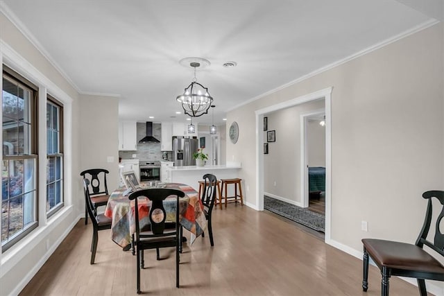 dining area featuring crown molding, a healthy amount of sunlight, an inviting chandelier, and light wood-type flooring