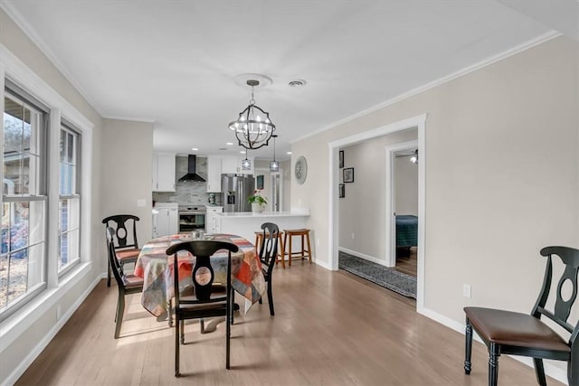 dining area featuring ornamental molding, a chandelier, and light wood-type flooring