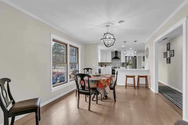 dining space featuring crown molding, wood-type flooring, and a chandelier