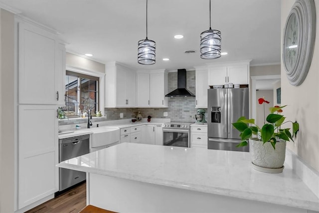 kitchen with white cabinetry, wall chimney range hood, pendant lighting, and stainless steel appliances