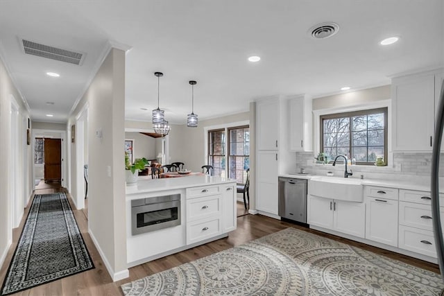 kitchen with stainless steel appliances, sink, pendant lighting, and white cabinets