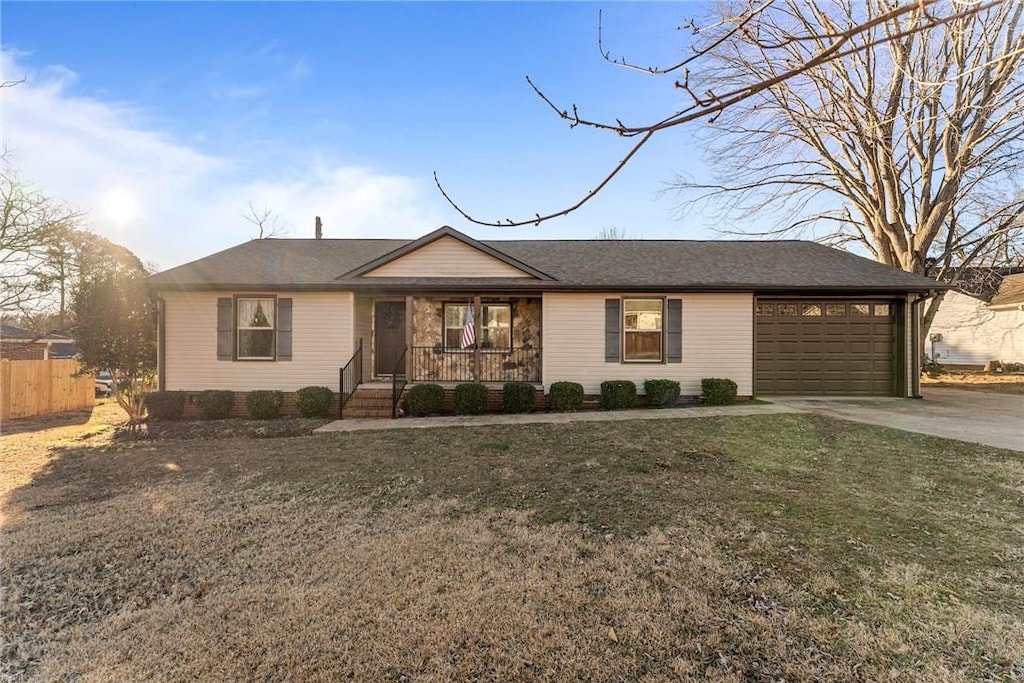 ranch-style house with a garage, a front yard, and covered porch