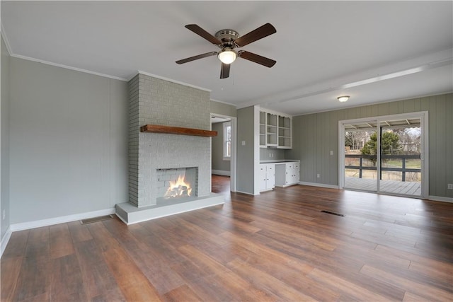 unfurnished living room featuring crown molding, wood-type flooring, and a fireplace