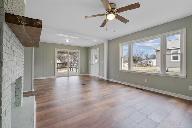 unfurnished living room with hardwood / wood-style floors, plenty of natural light, a fireplace, and ceiling fan